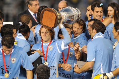 Uruguayan forward Diego Forlan (C) holds the trophy and celebrates with teammates at the end of the 2011 Copa America football tournament final against Paraguay held at the Monumental stadium in Buenos Aires, on July 24, 2011. Uruguay won 3-0 and became champion of the 2011 Copa America.  AFP PHOTO / JUAN MABROMATA (Photo credit should read JUAN MABROMATA/AFP/Getty Images)