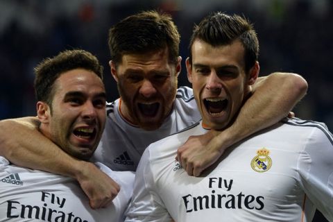 Real Madrid's Croatian midfielder Luka Modric (L) Real Madrid's midfielder Xabi Alonso (C) celebrate with Real Madrid's Welsh forward Gareth Bale after scoring during the UEFA Champions League quarterfinal first leg football match Real Madrid FC vs Borussia Dortmund at the Santiago Bernabeu stadium in Madrid on April 2, 2014.   AFP PHOTO/ GERARD JULIEN        (Photo credit should read GERARD JULIEN/AFP/Getty Images)