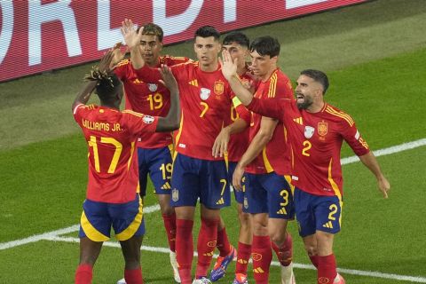 Spain's Alvaro Morata celebrates with teammates after Italy's Riccardo Calafiori, right, lies face down on the pitch after scoring an own goal during a Group B match between Spain and Italy at the Euro 2024 soccer tournament in Gelsenkirchen, Germany, Thursday, June 20, 2024. (AP Photo/Andreea Alexandru)