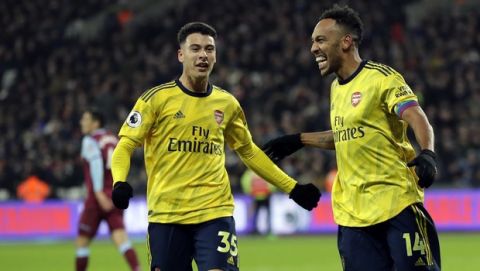 Arsenal's Pierre-Emerick Aubameyang, right, celebrates with Arsenal's Gabriel Martinelli after scoring his side's third goal duels for the ball with during the English Premier League soccer match between West Ham Utd and Arsenal at the London Stadium in London, Monday, Dec. 9, 2019. (AP Photo/Kirsty Wigglesworth)