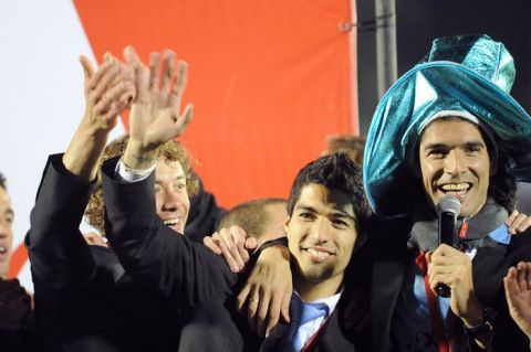 Uruguay's footballers  Luis Suarez (C) and Sebastian Abreu (R) celebrates with their teammates and supporters after winning the Copa America football tournament, at the Centenario stadium in Montevideo on July 25, 2011. Uruguay defeated Paraguay 3-0 on on July 24 to win a record 15th Copa America with striker Diego Forlan grabbing two goals to take his international tally to 31 and complete an incredible family story. AFP PHOTO / PABLO PORCIUNCULA (Photo credit should read PABLO PORCIUNCULA/AFP/Getty Images)