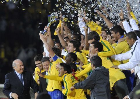 FIFA President Sepp Blatter (L) and Colombian President Juan Manuel Santos (3-L) smile as Brazilian players pose with the trophy after beating Portugal in the FIFA 2011 Under-20 World Cup final match in Bogota on August 20, 2011. Brazil won 3-2 in overtime. AFP PHOTO / AIZAR RALDES (Photo credit should read AIZAR RALDES/AFP/Getty Images)