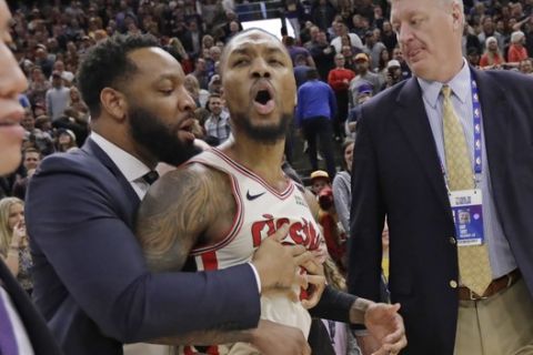 Portland Trail Blazers guard Damian Lillard (0) is held back following the team's NBA basketball game against the Utah Jazz on Friday, Feb. 7, 2020, in Salt Lake City. The Jazz won 117-114. (AP Photo/Rick Bowmer)