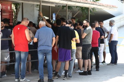 Οπαδοί του Ολυμπιακού συνομιλούν μεταξύ τους σε μία από τις ουρές στα εκδοτήρια του ΣΕΦ