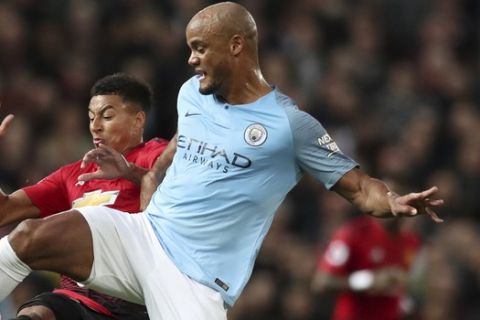 Manchester United's Jesse Lingard fights for the ball with Manchester City's Vincent Kompany, right, during the English Premier League soccer match between Manchester United and Manchester City at Old Trafford Stadium in Manchester, England, Wednesday April 24, 2019. (AP Photo/Jon Super)