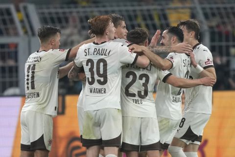 St. Pauli's team players celebrate after Eric Smith scored their side's first goal during the German Bundesliga soccer match between Borussia Dortmund and St. Pauli at the Signal-Iduna Park in Dortmund, Germany, Friday, Oct. 18, 2024. (AP Photo/Martin Meissner)