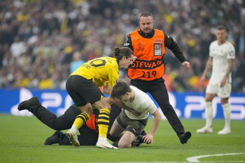 Dortmund's Marcel Sabitzer tries to hold up a pitch invader followed by security during the Champions League final soccer match between Borussia Dortmund and Real Madrid at Wembley stadium in London, Saturday, June 1, 2024. (AP Photo/Kin Cheung)