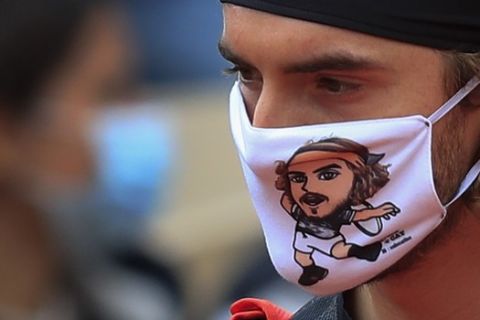 Greece's Stefanos Tsitsipas wears a face mask with his own caricature prior to his third round match of the French Open tennis tournament against Slovenia's Aljaz Bedene at the Roland Garros stadium in Paris, France, Saturday, Oct. 3, 2020. (AP Photo/Michel Euler)