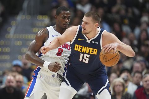 Denver Nuggets center Nikola Jokic, front, looks to pass the ball as Detroit Pistons center Jalen Duren defends in the first half of an NBA basketball game Saturday, Dec. 28, 2024, in Denver. (AP Photo/David Zalubowski)