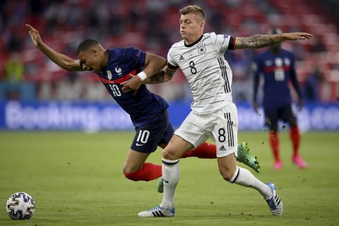 France's Kylian Mbappe, left, and Germany's Toni Kroos challenge for the ball during the Euro 2020 soccer championship group F match between France and Germany at the Allianz Arena stadium in Munich, Tuesday, June 15, 2021. (Matthias Hangst/Pool via AP)