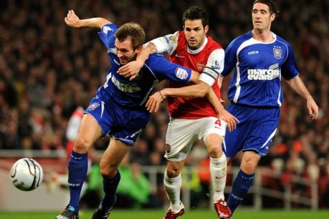 Arsenal's Spanish midfielder Cesc Fabregas (C) vies for the ball against Ipswich's Gareth Mcauley (L) during the League Cup semi-final 2nd leg football match at the Emirates Stadium in London on January 25, 2011. AFP PHOTO / Adrian DennisFOR EDITORIAL USE ONLY Additional licence required for any commercial/promotional use or use on TV or internet (except identical online version of newspaper) of Premier League/Football League photos. Tel DataCo +44 207 2981656. Do not alter/modify photo. (Photo credit should read ADRIAN DENNIS/AFP/Getty Images)