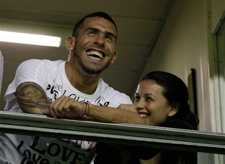 England's Manchester City's soccer player Carlos Tevez, left, from Argentina, accompanied by his wife Vanesa Mansilla, laughs before a Copa Libertadores soccer match between Argentina's Boca Juniors and Brazil's Fluminense in Buenos Aires, Argentina, Thursday, May 17, 2012. (AP Photo/Eduardo Di Baia)