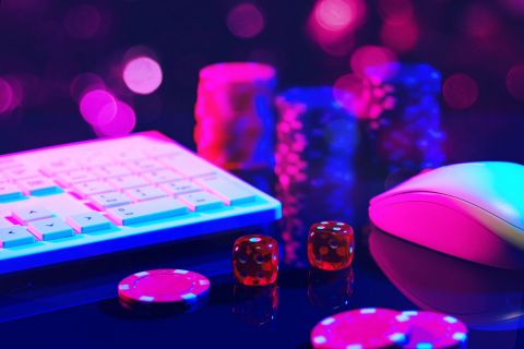 Close-up shot of red dice on a pink surface with a computer keyboard and mouse in the background.