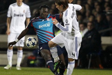 Olympique Lyon's Bafetimbi Gomis (L) challenges Sergio Ramos (R) of Real Madrid during their Champions League soccer match at the Gerland stadium in Lyon February 22, 2011.    REUTERS/Robert Pratta (FRANCE - Tags: SPORT SOCCER)