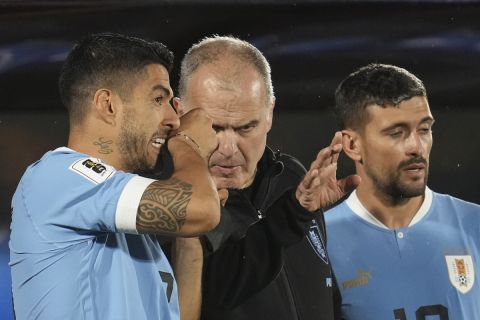 Uruguay's coach Marcelo Bielsa, center, gives instructions to Luis Suarez, left, before entering the field during a qualifying soccer match against Bolivia for the FIFA World Cup 2026 at Centenario stadium in Montevideo, Uruguay, Tuesday, Nov. 21, 2023. (AP Photo/Matilde Campodonico)