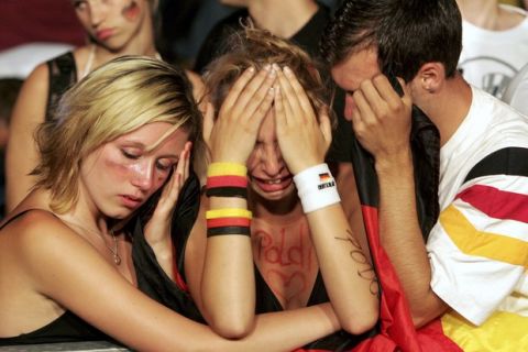 BERLIN - JULY 4:  Stunned Germany soccer fans react after watching the FIFA World Cup 2006 Semi Finals match between Germany and Italy at the Fan Fest outdoor viewing area at the Brandenburg Gate July 4, 2006 in Berlin, Germany. Germany lost 2-0. (Photo by Sean Gallup/Getty Images)